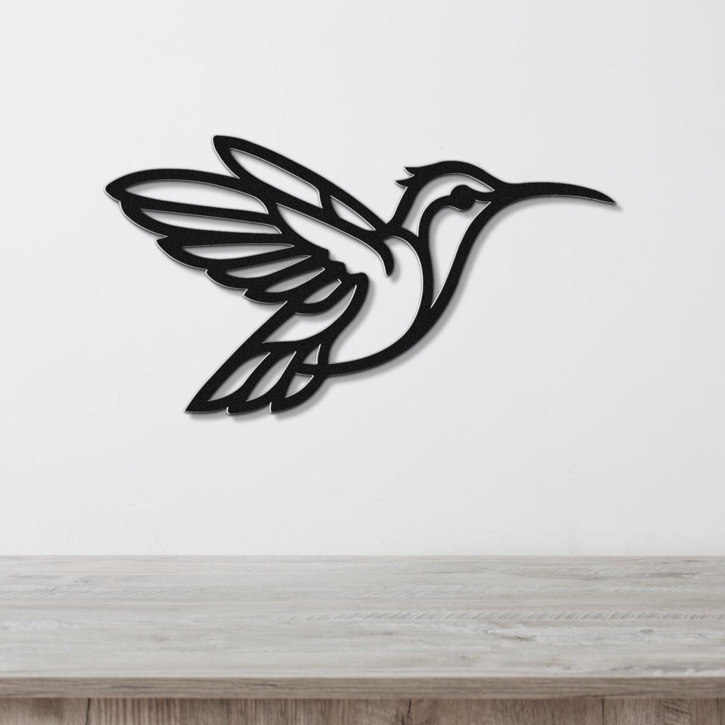 Black metal hummingbird wall art with wing and tail cutouts, mounted on a white wall above a light wood counter.