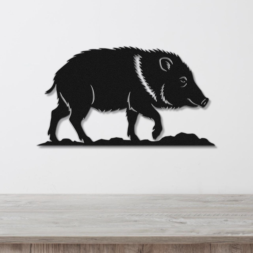 Black metal wall art silhouette of a javelina with detailed fur and facial features, mounted on a white wall above a wooden surface.