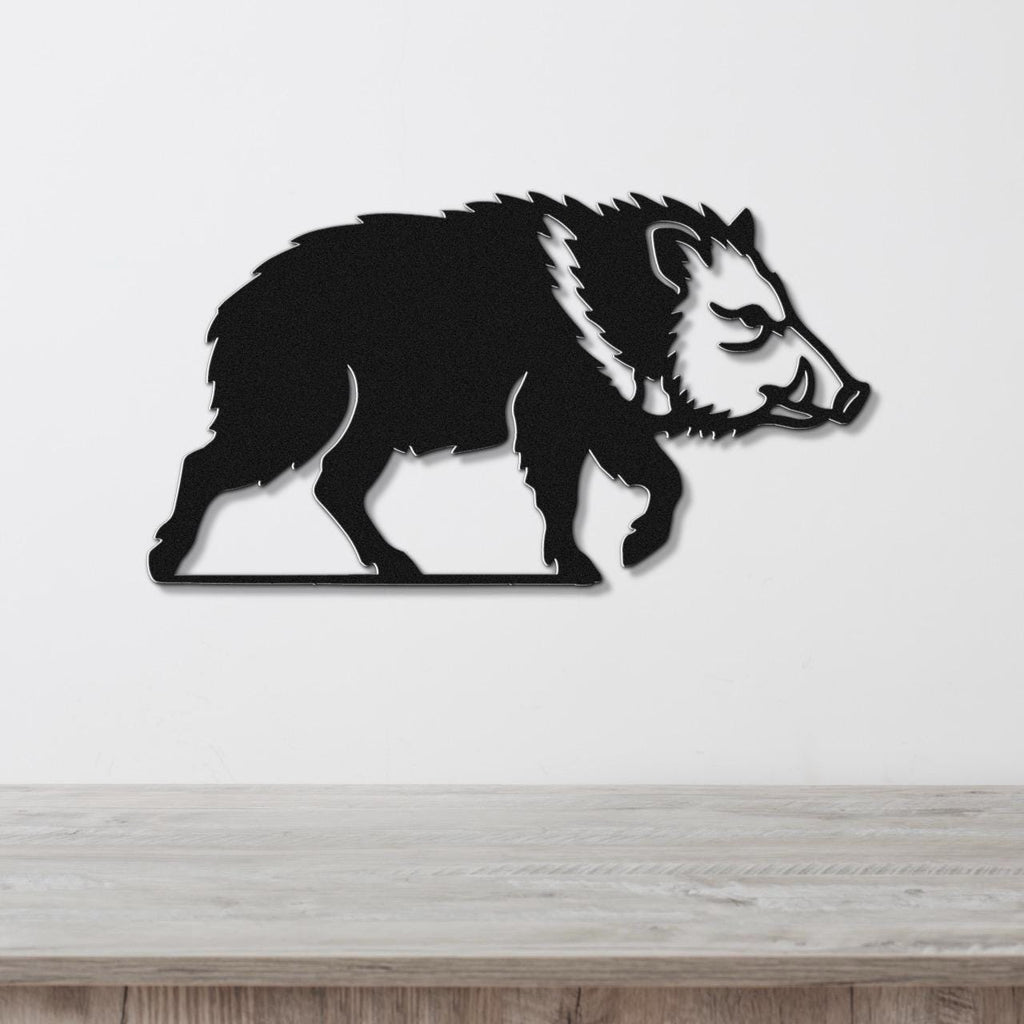 Black metal javelina wall art with a silhouette cutout design, mounted on a white wall above a light wood surface.