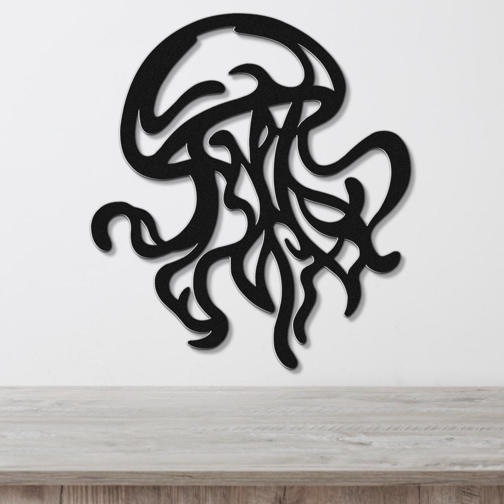 Black metal jellyfish wall art with flowing tentacle cutouts, mounted on a white wall above a light wood surface.