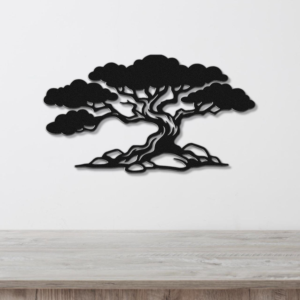 Black metal wall art in a wind-sculpted juniper tree silhouette with detailed branches and roots, mounted on a white wall above a light wood surface.