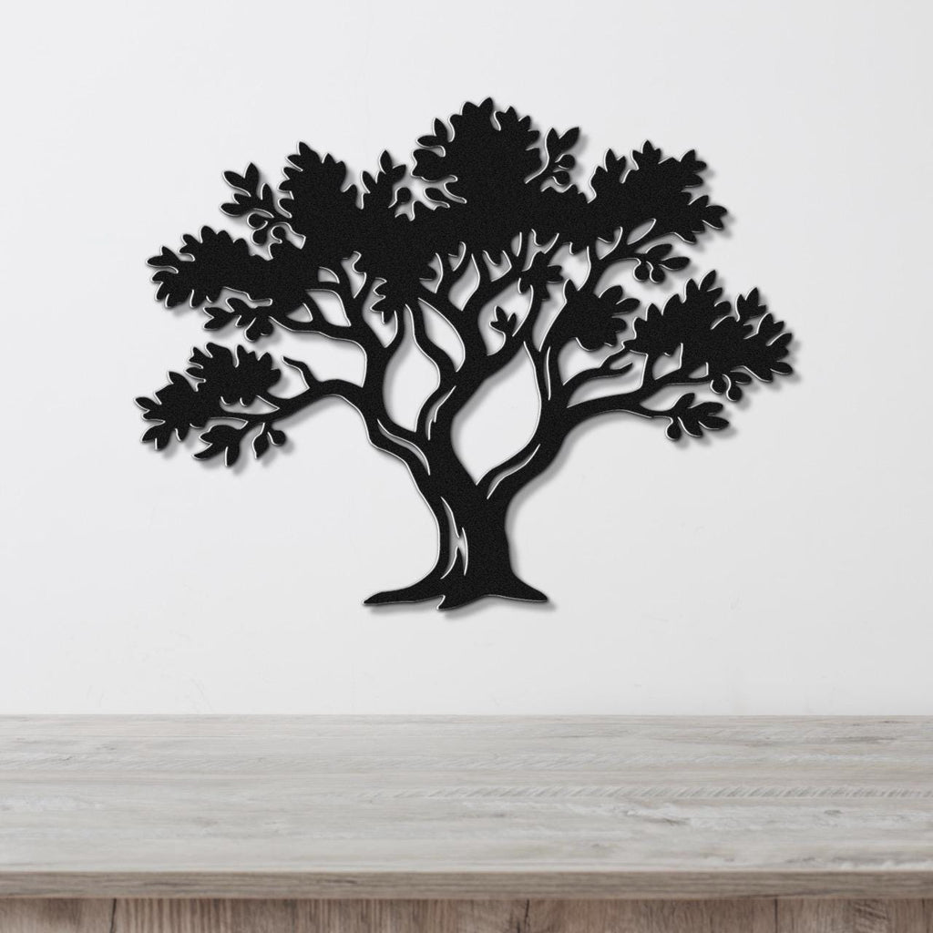 Black metal tree wall art with leaf and branch cutouts, mounted on a white wall above a light wood counter.