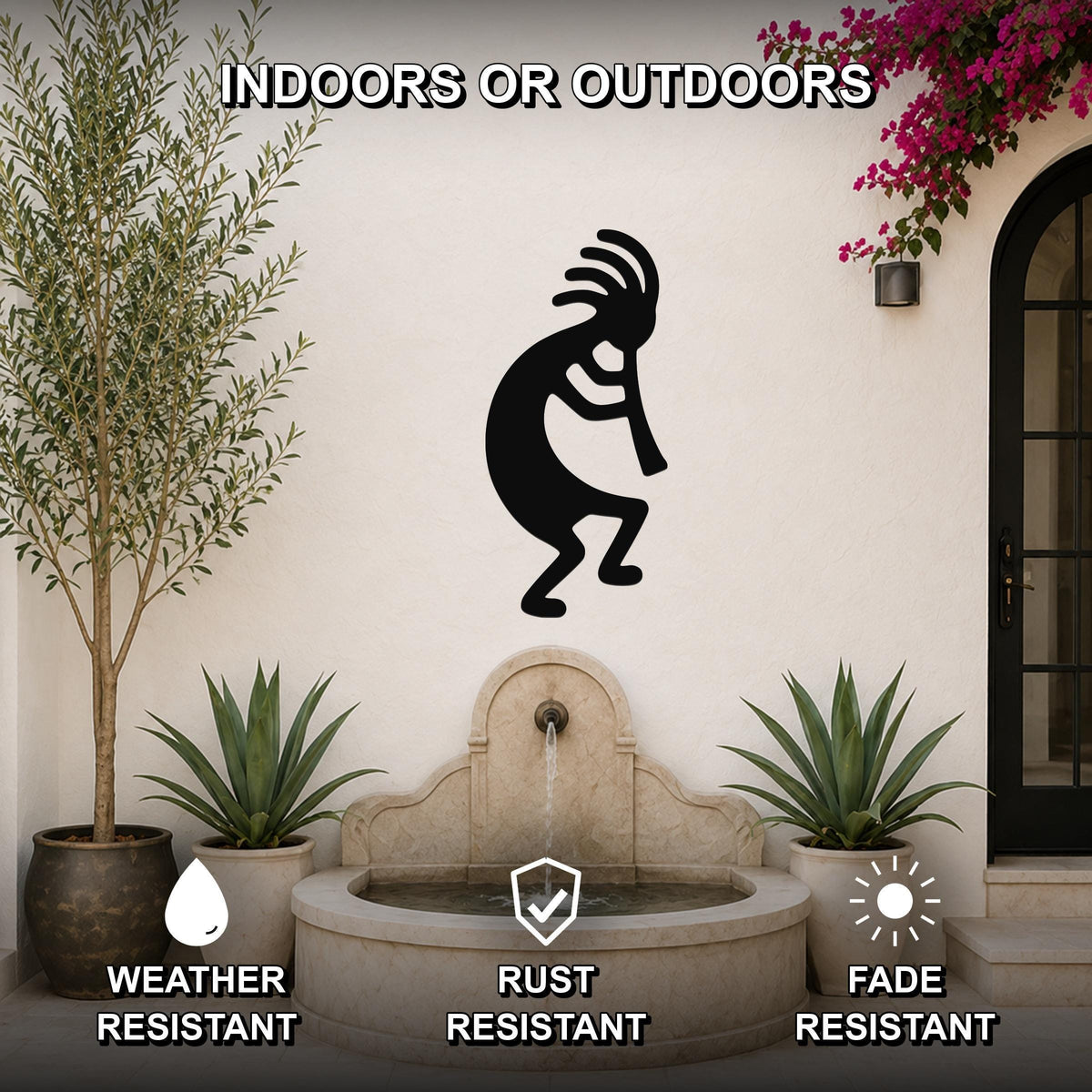 Black metal Kokopelli wall art silhouette with feathered headdress and flute, mounted on an outdoor patio wall above a stone fountain, flanked by potted plants.