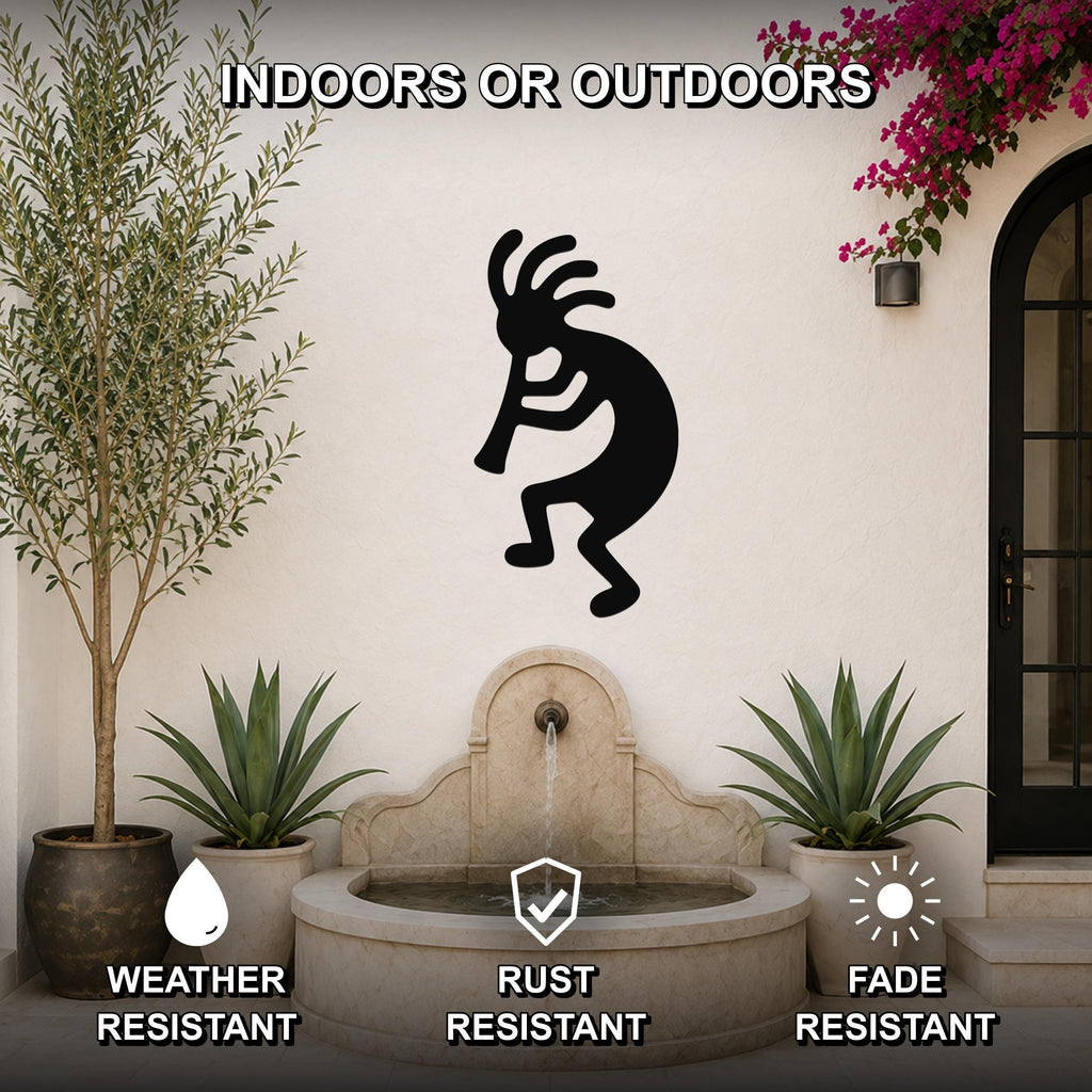 Black metal Kokopelli wall art silhouette mounted on an outdoor wall above a stone fountain, flanked by potted plants and a flowering vine.