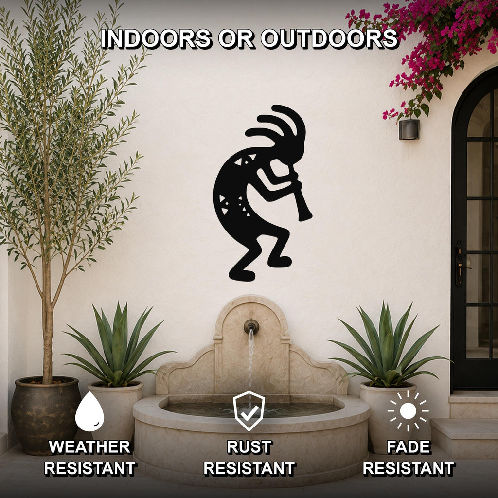 Black metal Kokopelli wall art silhouette with internal cutout details, mounted on an outdoor wall above a stone fountain in a patio setting.