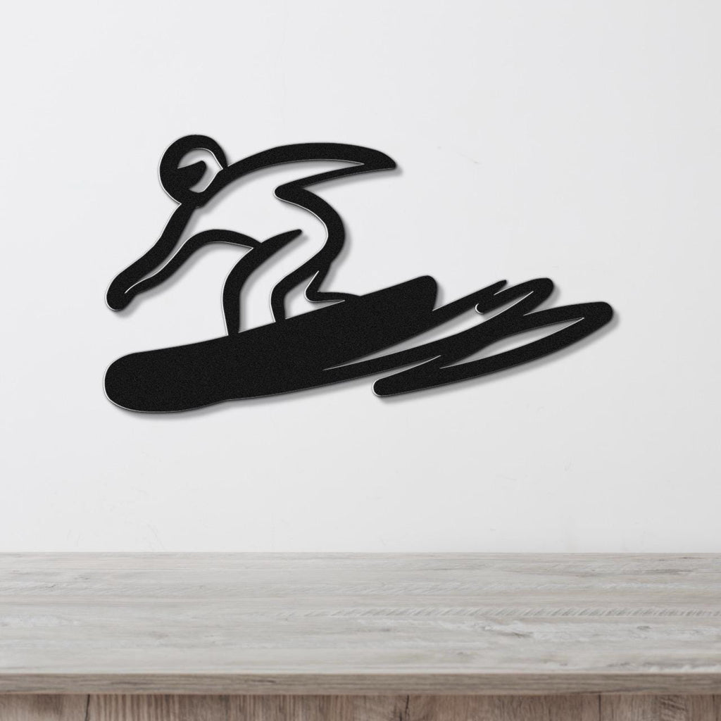 Black metal wall art featuring a bold silhouette of a snowboarder in motion, mounted on a white wall above a wooden surface.