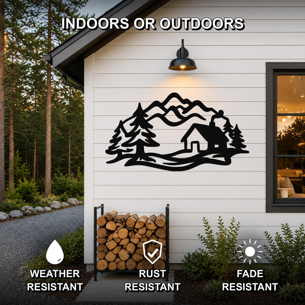 Black metal wall art with a mountain cabin and pine tree silhouette, mounted on a white exterior wall above a firewood rack, weather and fade resistant.