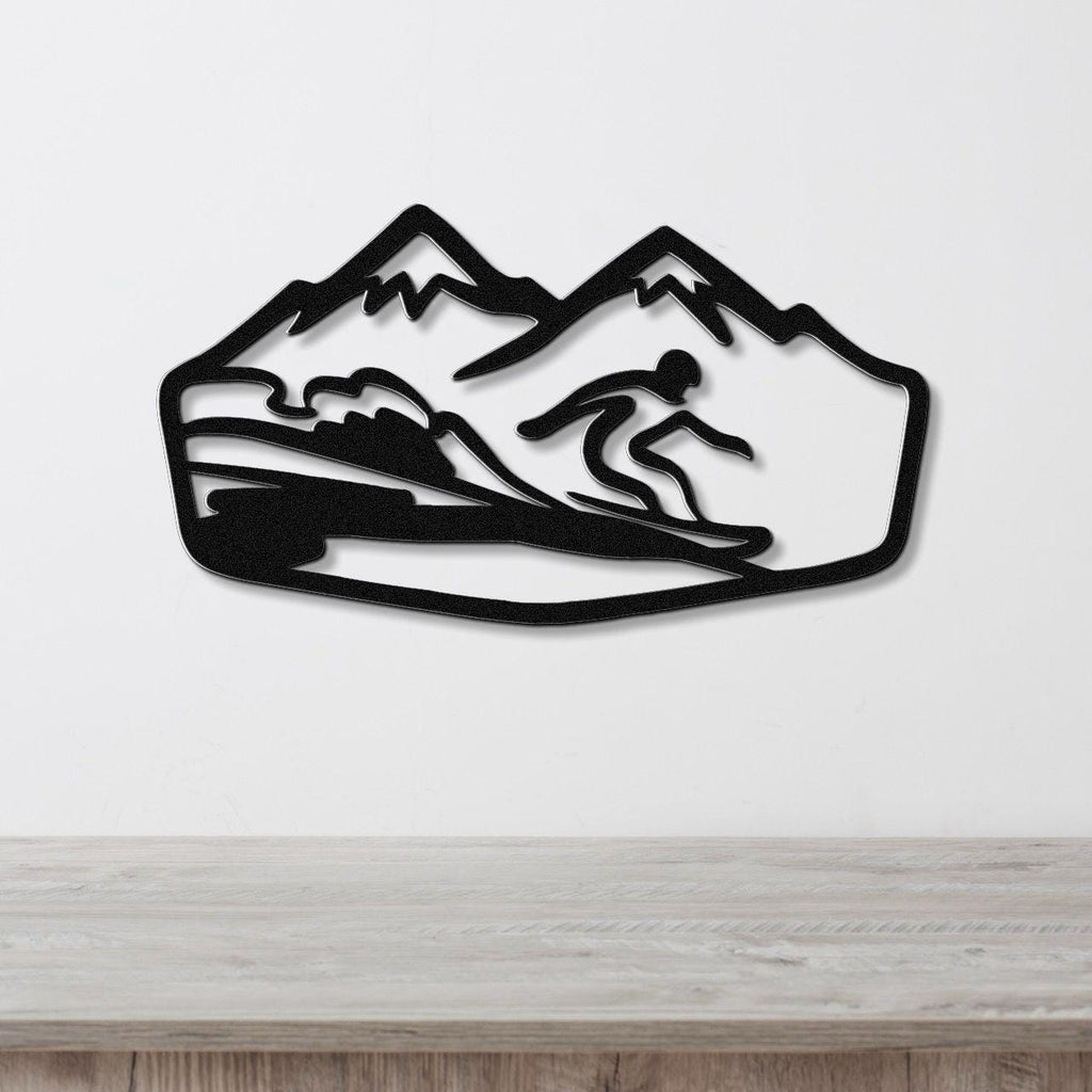 Black metal wall art featuring a snowboarder silhouette in motion against a mountain backdrop, mounted on a white wall above a wooden surface.