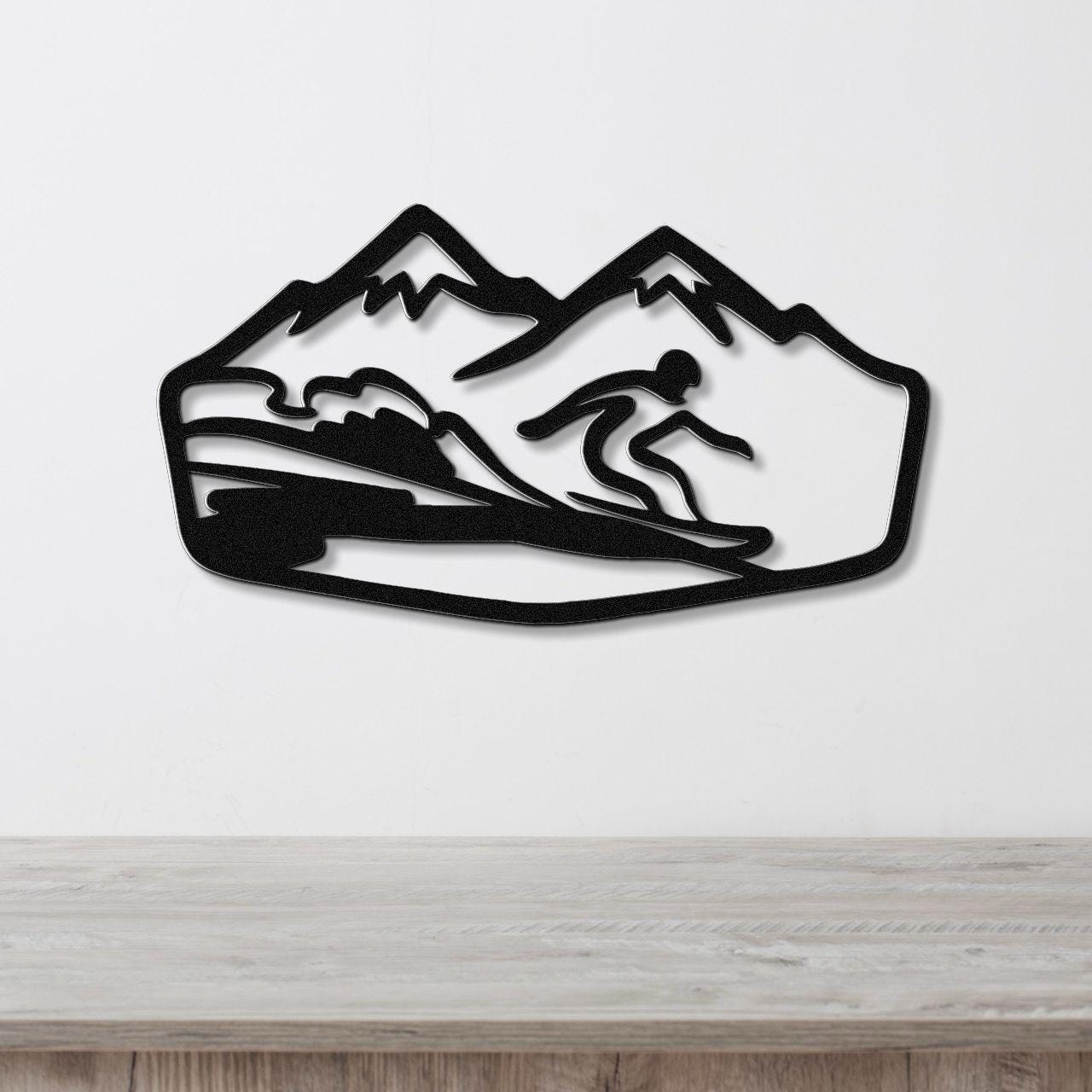 Black metal wall art featuring a snowboarder silhouette in motion against a mountain backdrop, mounted on a white wall above a wooden surface.