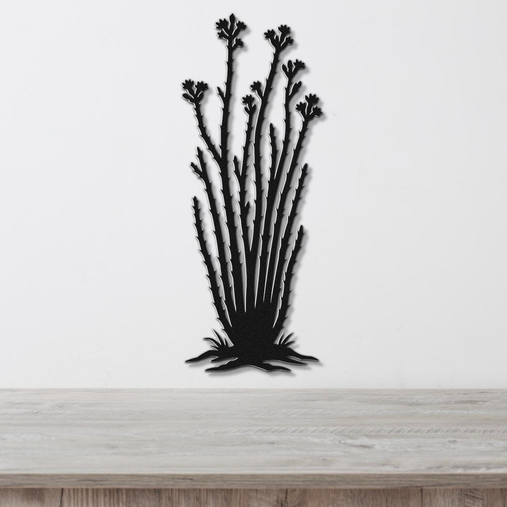 Black metal wall art cutout of an ocotillo plant with branching stems and flower clusters, mounted on a white wall above a light wood surface.