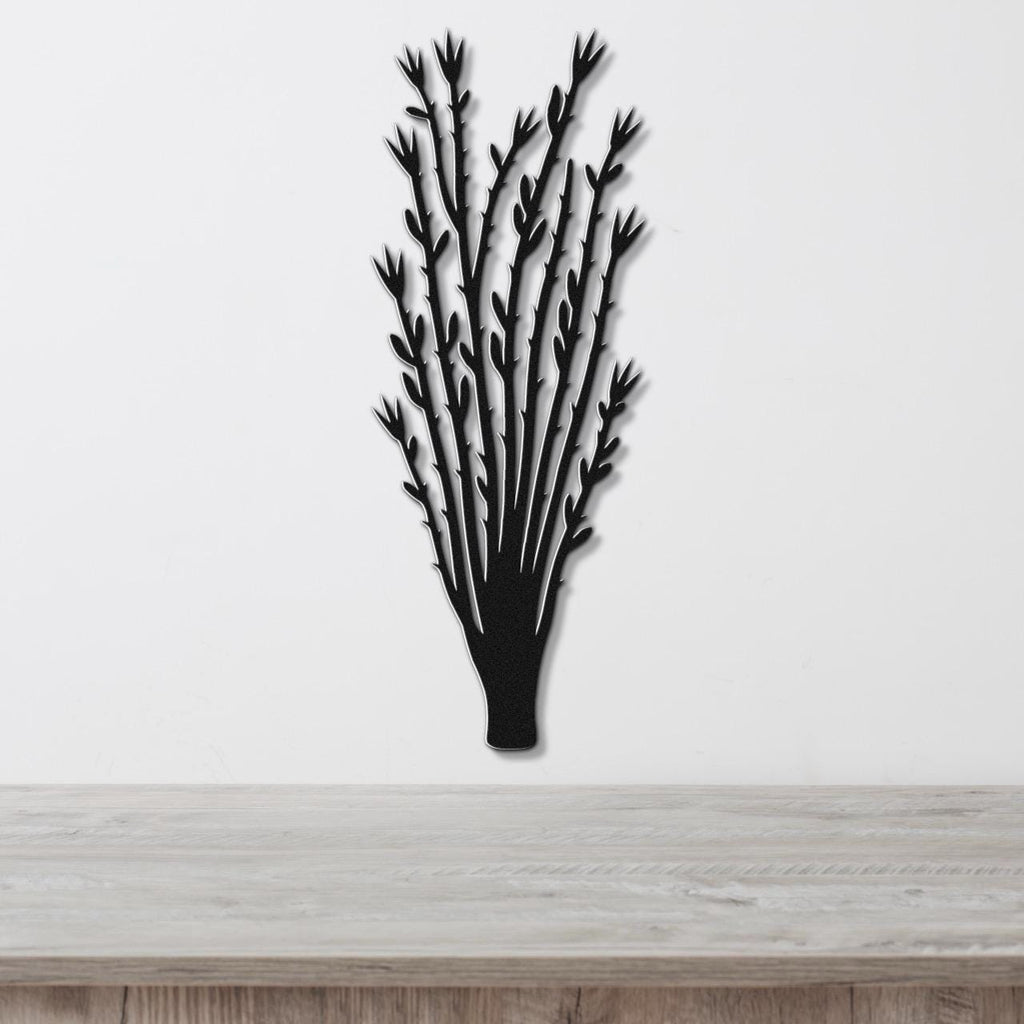 Black metal wall art cutout of an ocotillo plant with branching stems and leaf details, mounted on a white wall above a light wood surface.