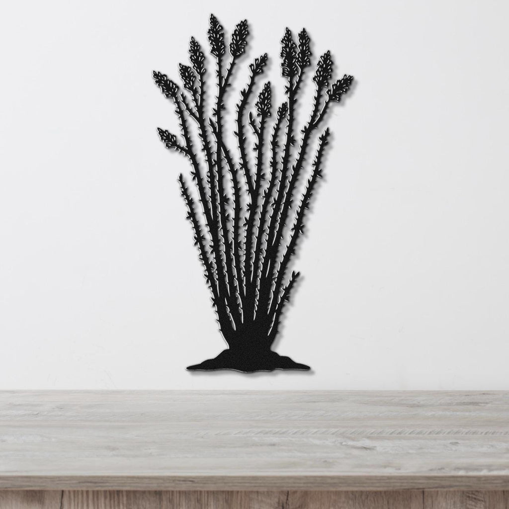 Black metal wall art silhouette of an ocotillo plant with spiny stems and clustered flower cutouts, mounted on a white wall above a light wood surface.