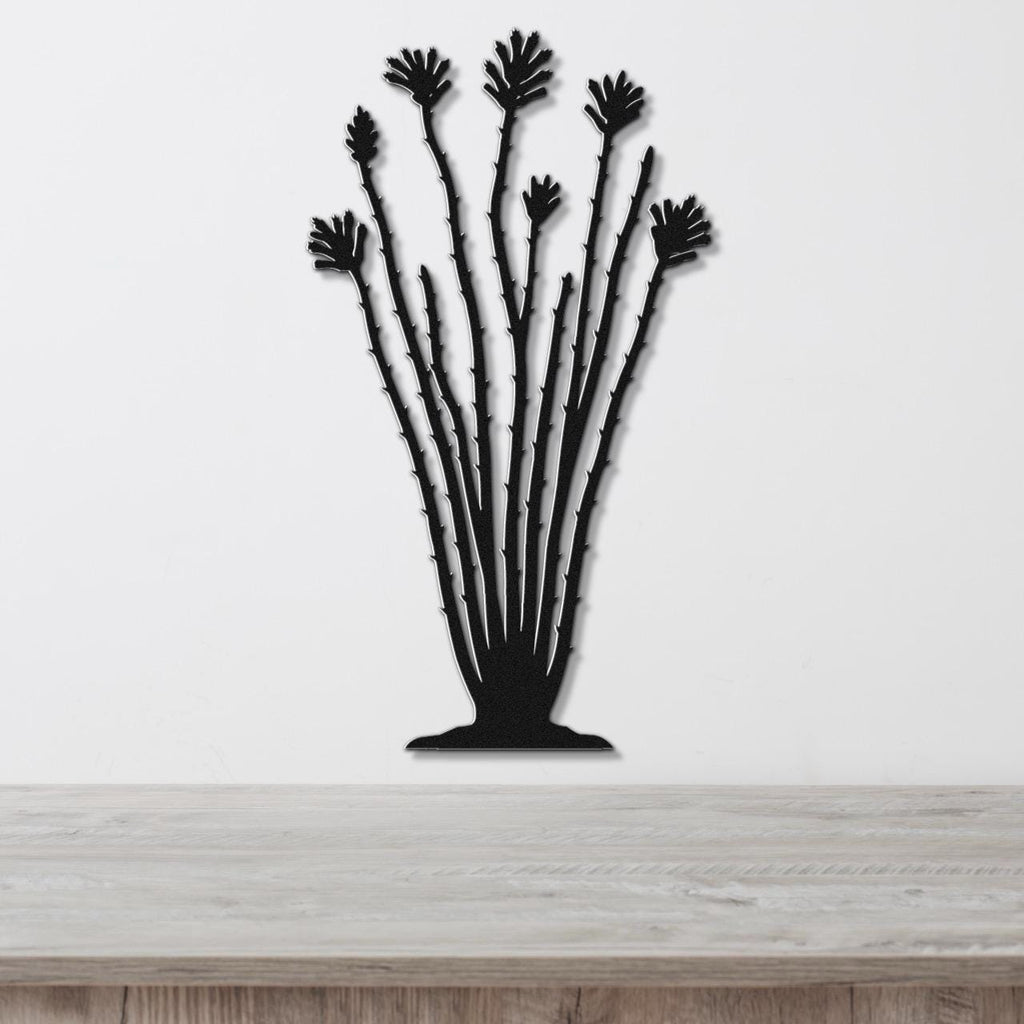 Black metal ocotillo wall sculpture with spiny stems and fan-shaped leaf cutouts, mounted on a white wall above a wooden surface.
