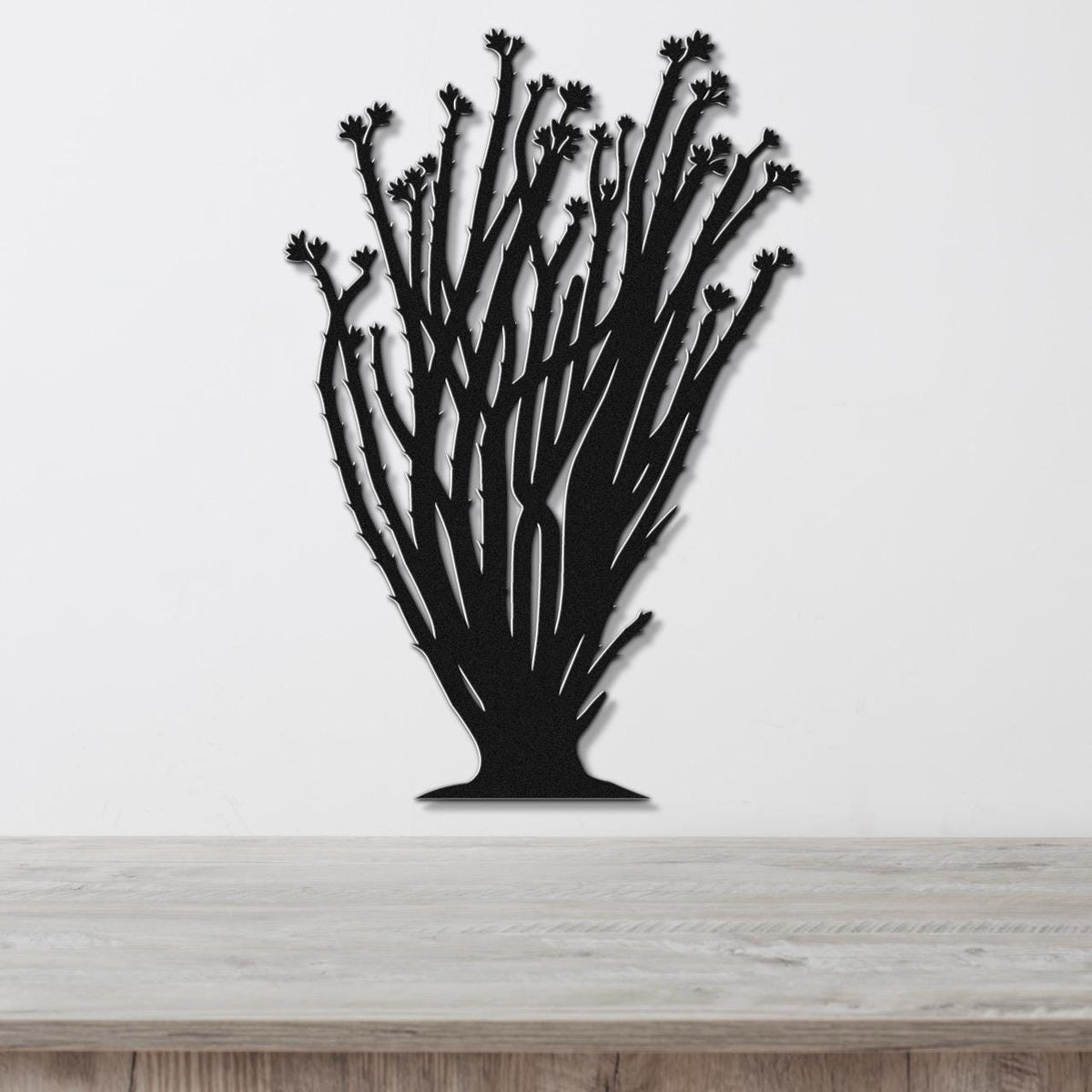 Black metal ocotillo wall art with branching stems and flower cutouts, mounted on a white wall above a wooden counter.