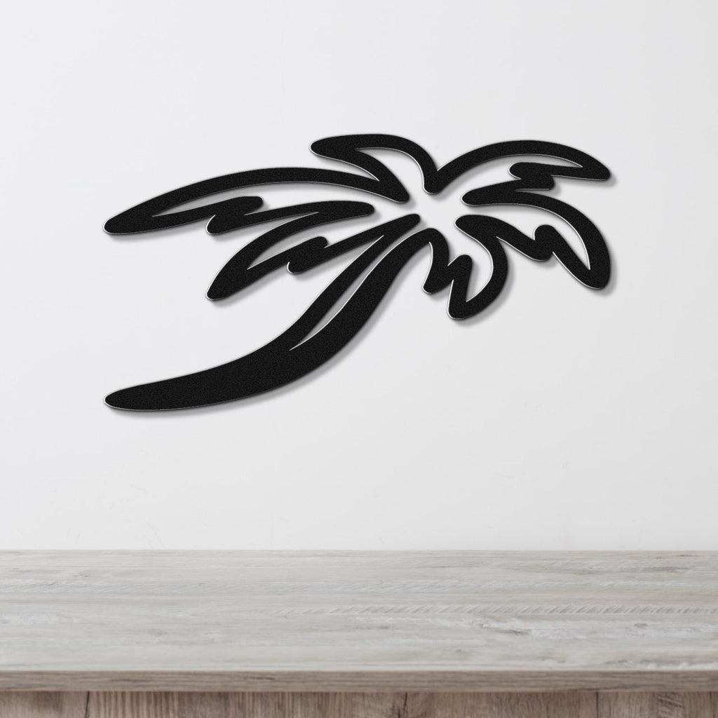 Black metal palm tree wall art with layered frond cutouts, mounted on a white wall above a light wood surface.