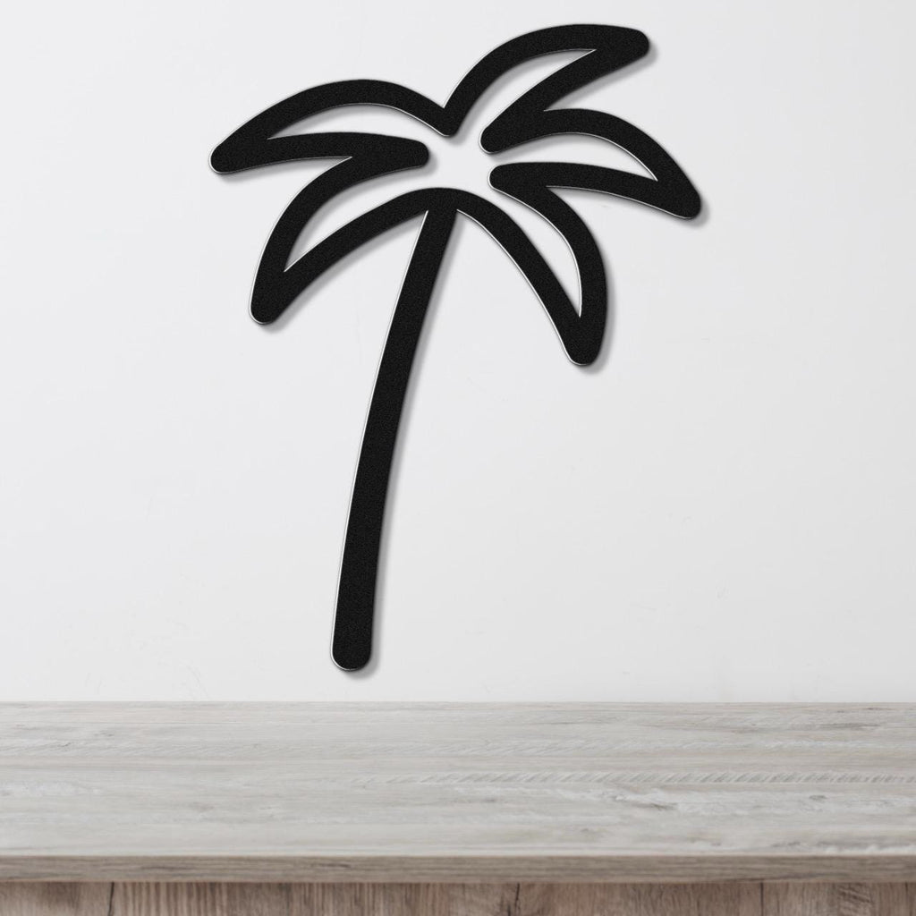 Black metal palm tree wall art with leaf cutouts, mounted on a white wall above a light wood surface.