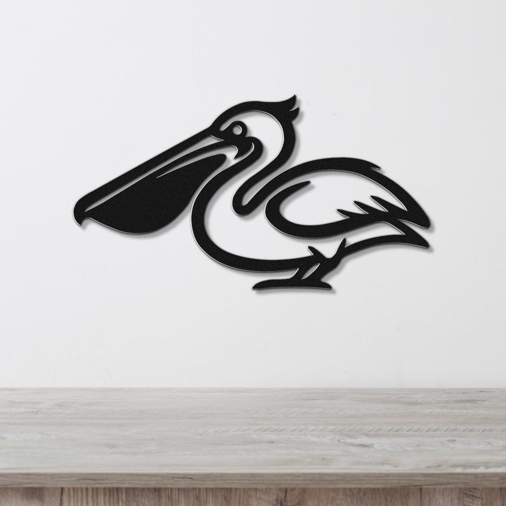 Black metal pelican wall art with a cutout silhouette design, mounted on a white wall above a light wood surface.