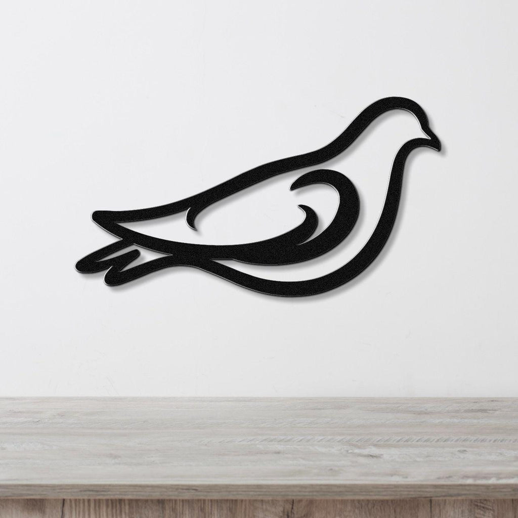 Black metal pigeon wall art with a bold silhouette and internal cutout details, mounted on a white wall above a light wood surface.