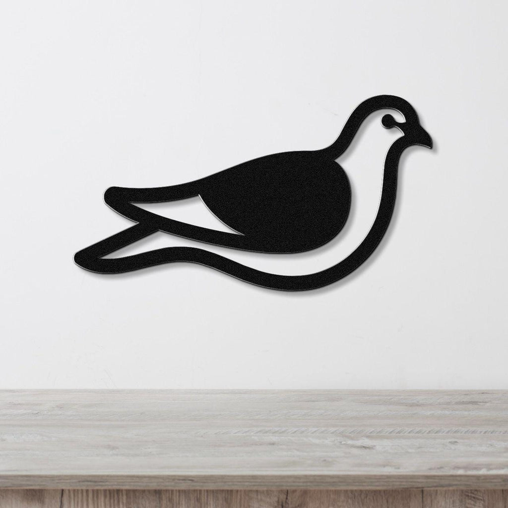 Black metal pigeon wall art with a cutout silhouette design, mounted on a white wall above a light wood surface.