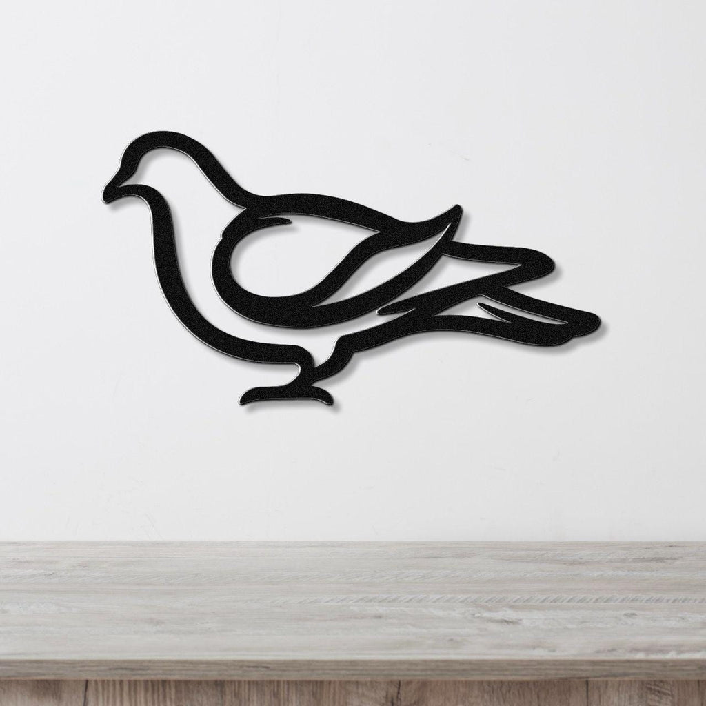 Black metal pigeon wall art with a minimalist silhouette design, mounted on a white wall above a light wood surface.
