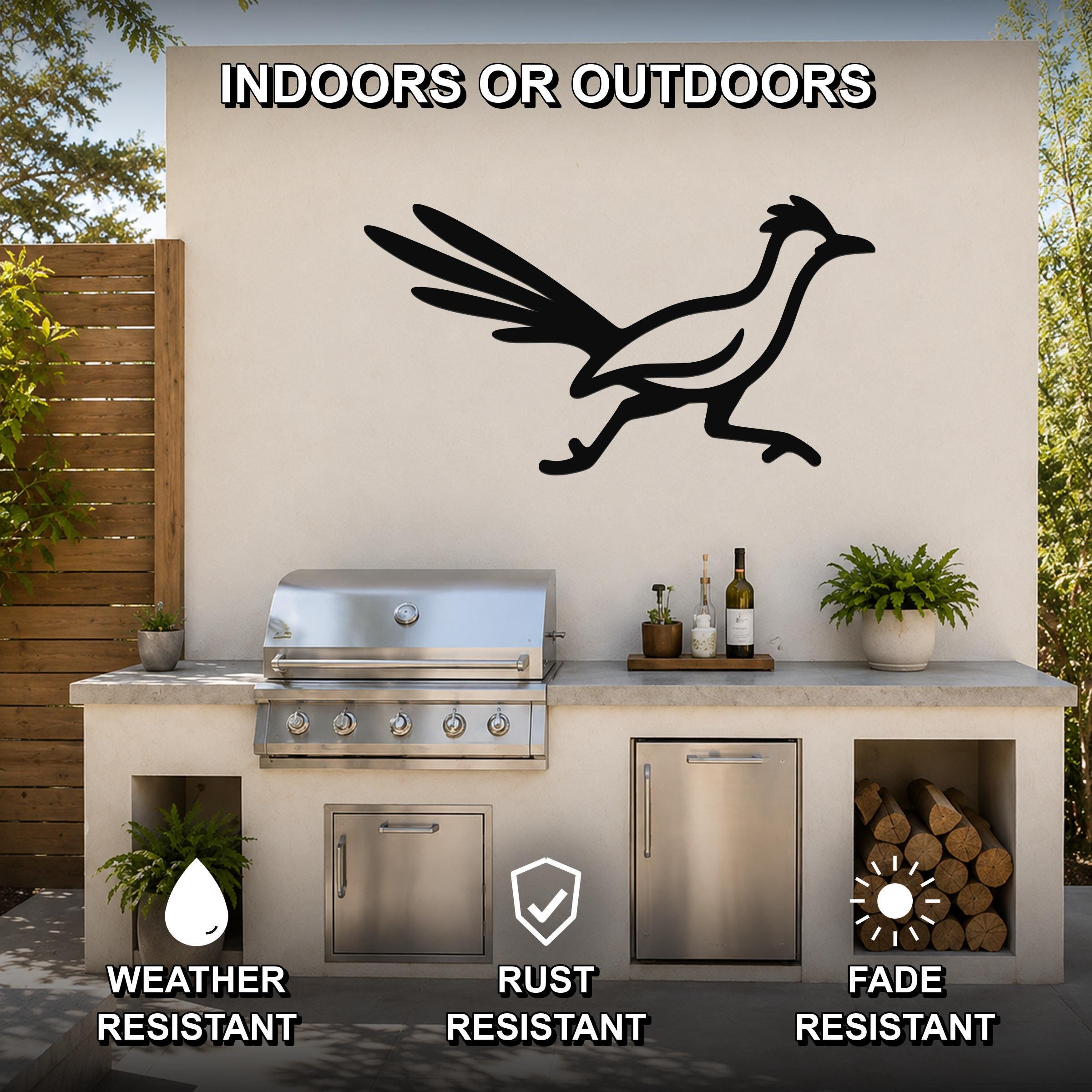 Black metal roadrunner wall art silhouette mounted on an outdoor kitchen wall above a stainless steel grill, with visible weather, rust, and fade resistance icons.