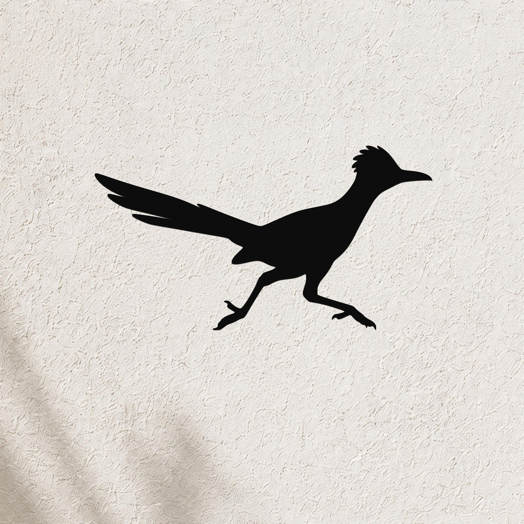 Black metal roadrunner wall art silhouette with outstretched wings and long tail, mounted on a textured white wall.