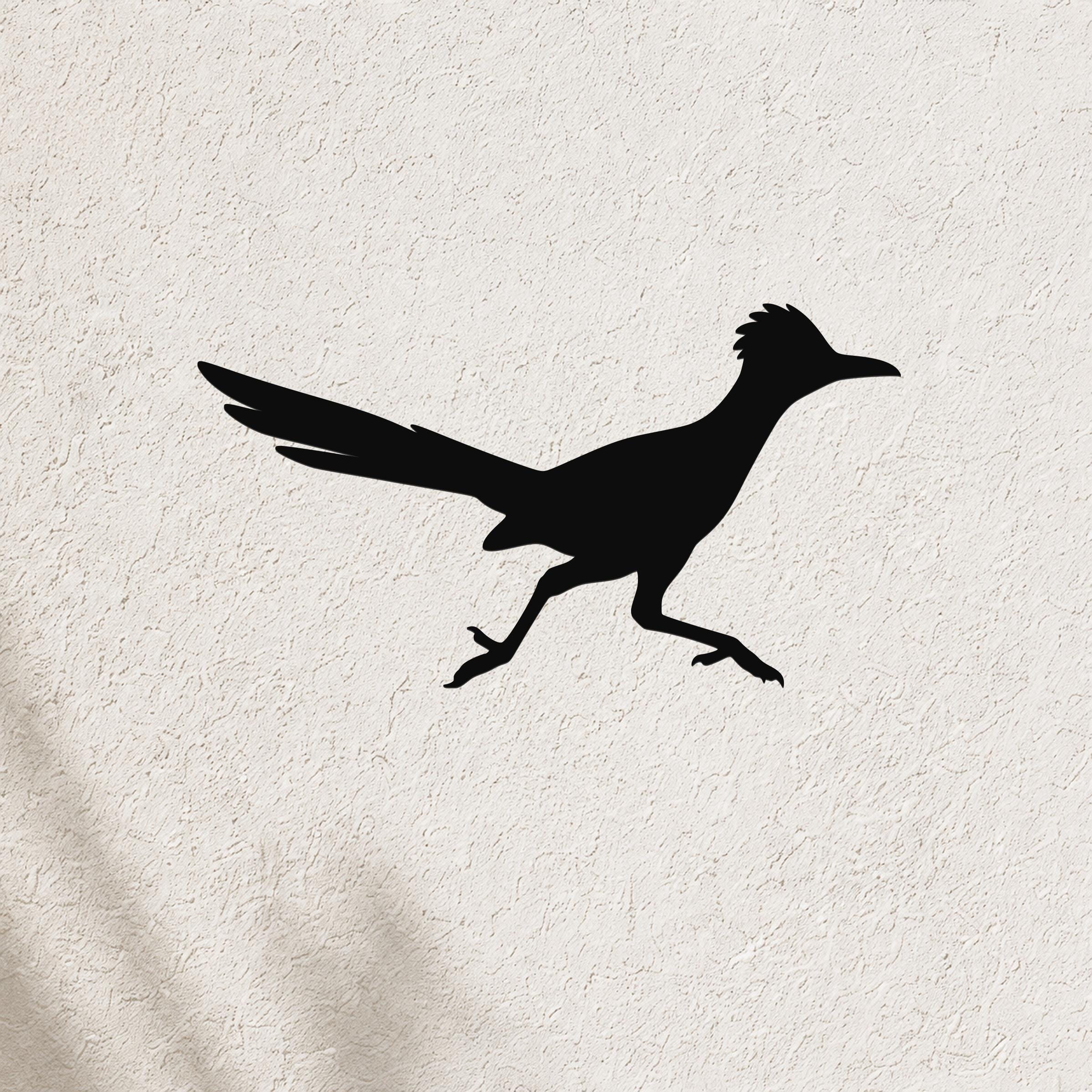 Black metal roadrunner wall art silhouette with outstretched wings and long tail, mounted on a textured white wall.