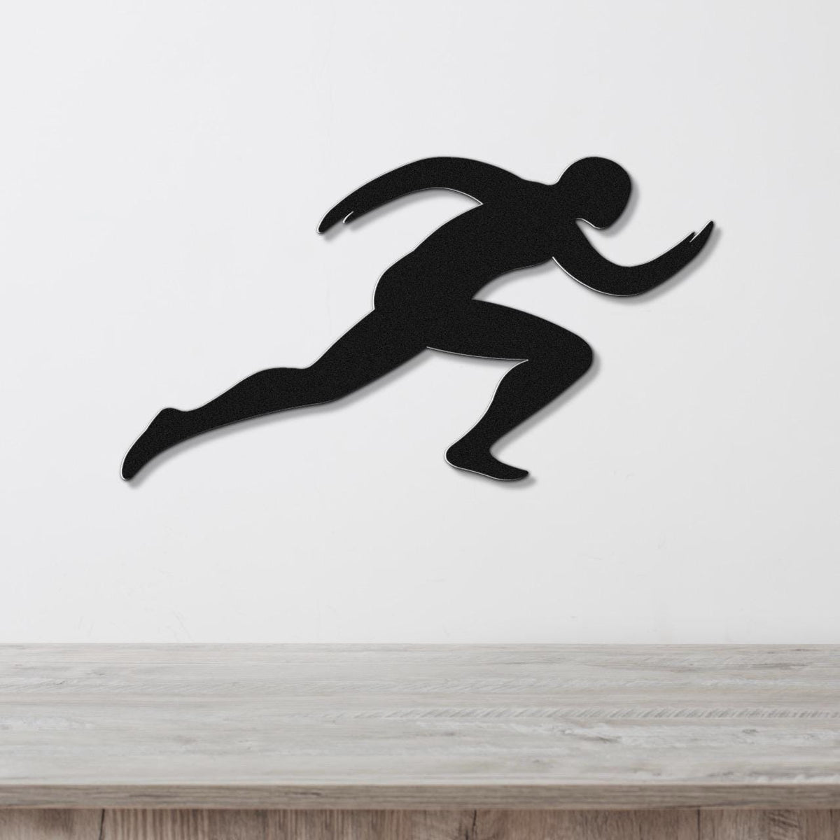 Black metal runner wall art with motion-line cutouts, mounted on a white wall above a light wood counter.