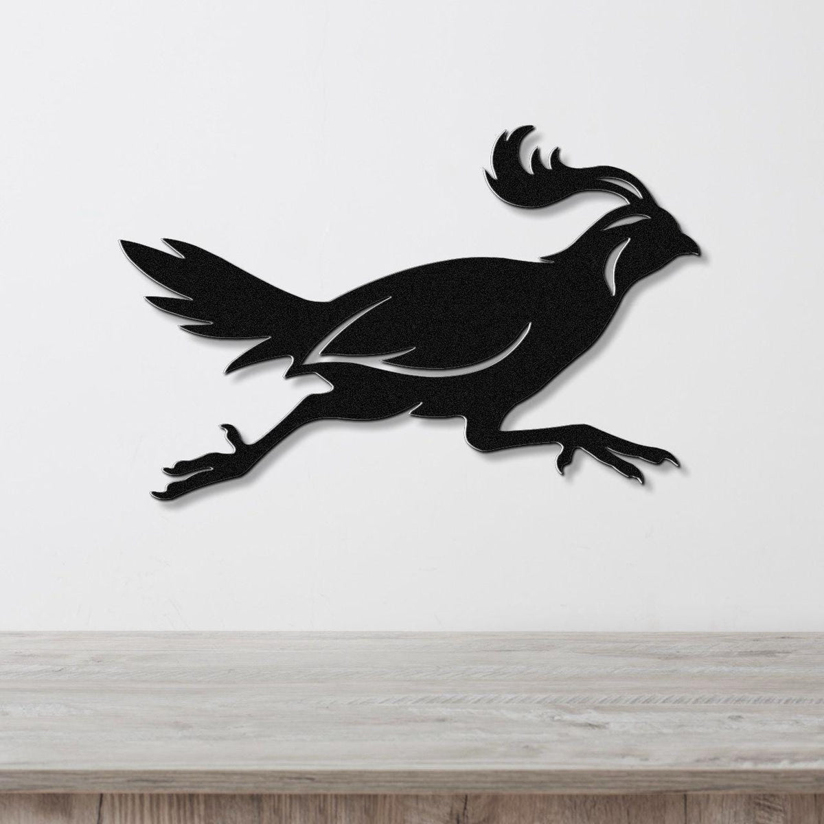 Black metal quail wall art in a running silhouette, mounted on a white wall above a light wood counter.