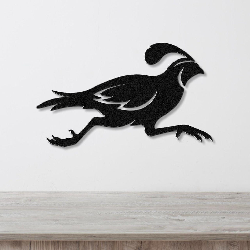 Black metal quail wall art in a running silhouette with internal feather cutouts, mounted on a white wall above a light wood counter.
