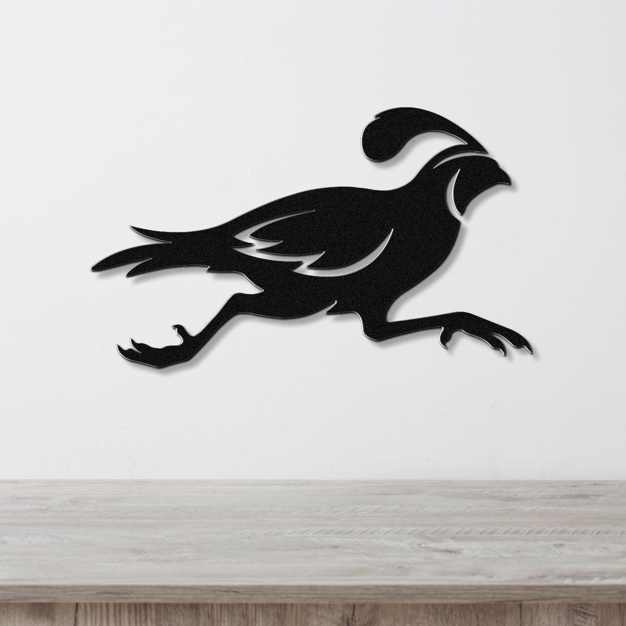 Black metal quail wall art in a running silhouette with internal feather cutouts, mounted on a white wall above a light wood counter.