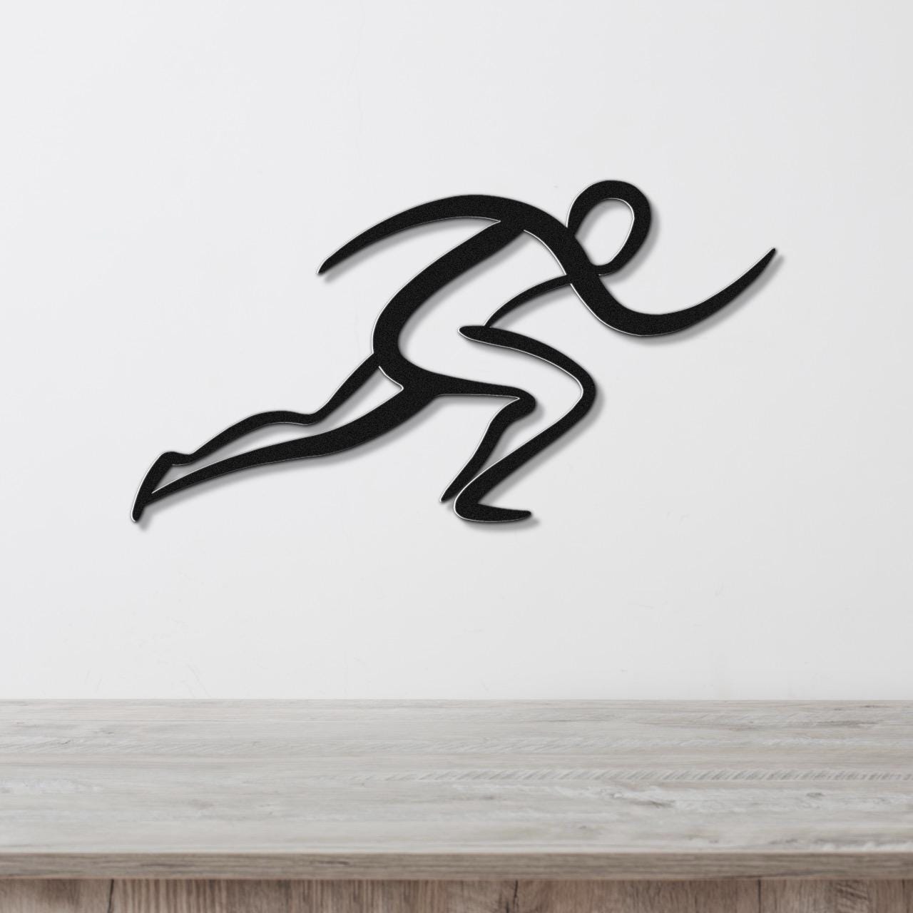 Black metal runner wall art with dynamic motion-line cutouts, mounted on a white wall above a light wood countertop.