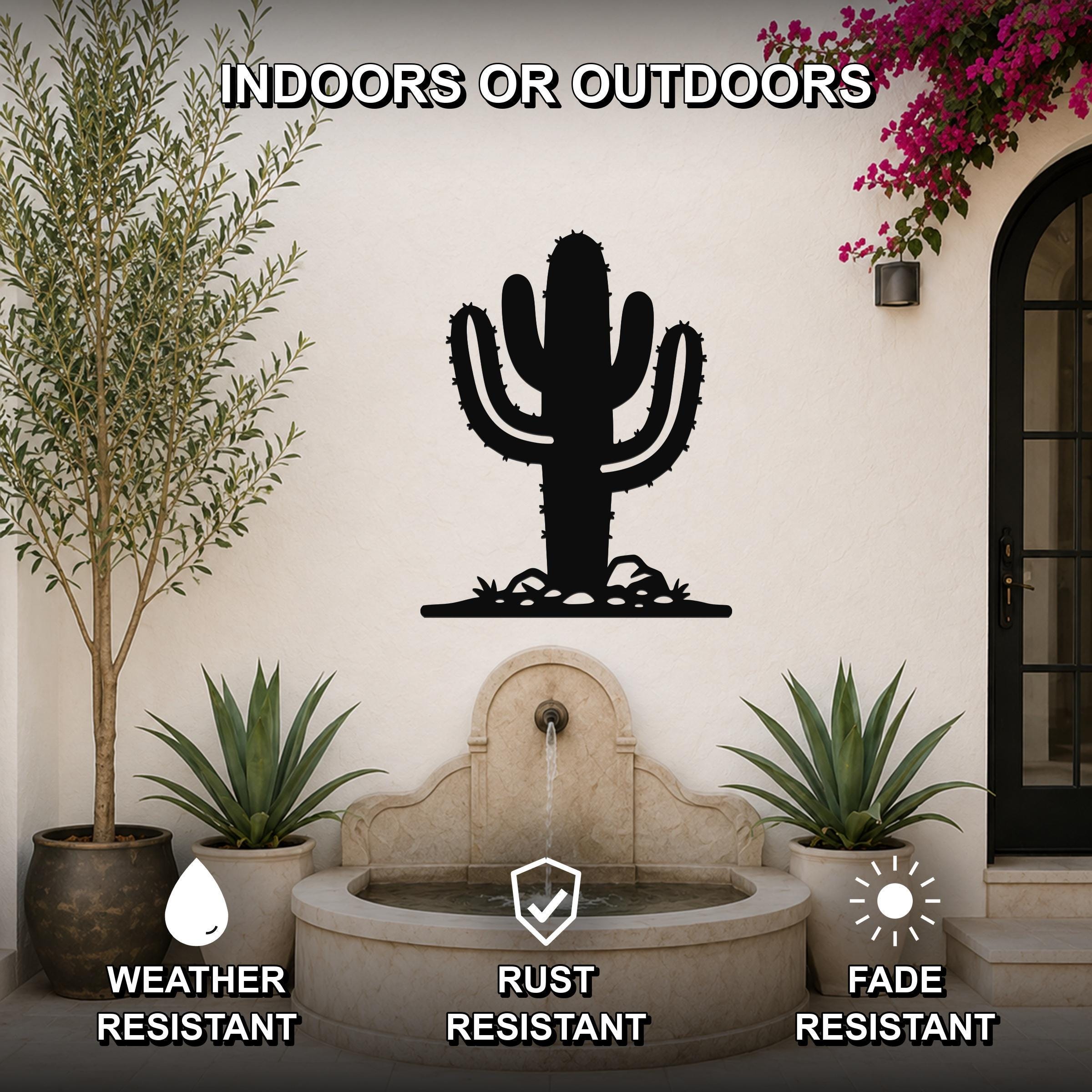 Black metal saguaro cactus wall art with spines and base cutouts, mounted on an outdoor wall above a stone fountain in a patio setting.