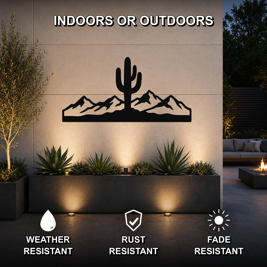 Black metal wall art featuring a saguaro cactus and mountain silhouette, mounted on an outdoor patio wall above a planter with warm uplighting.