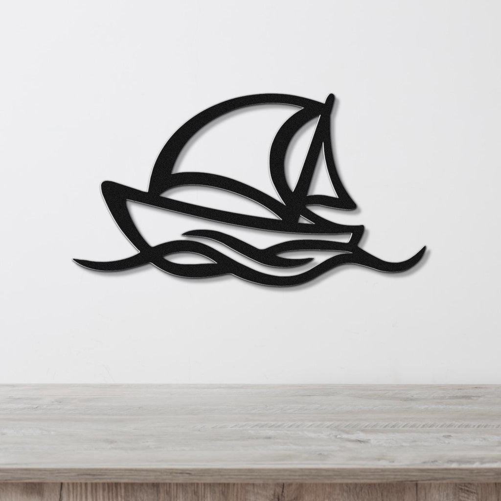 Black metal wall art silhouette of a sailboat with wave cutouts, mounted on a white wall above a wooden surface.
