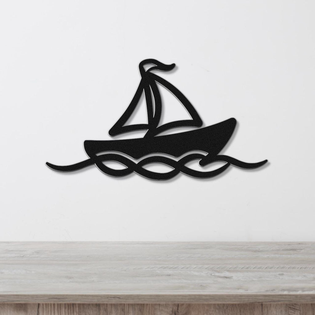 Black metal sailboat wall art with wave cutouts, mounted on a white wall above a light wood surface.