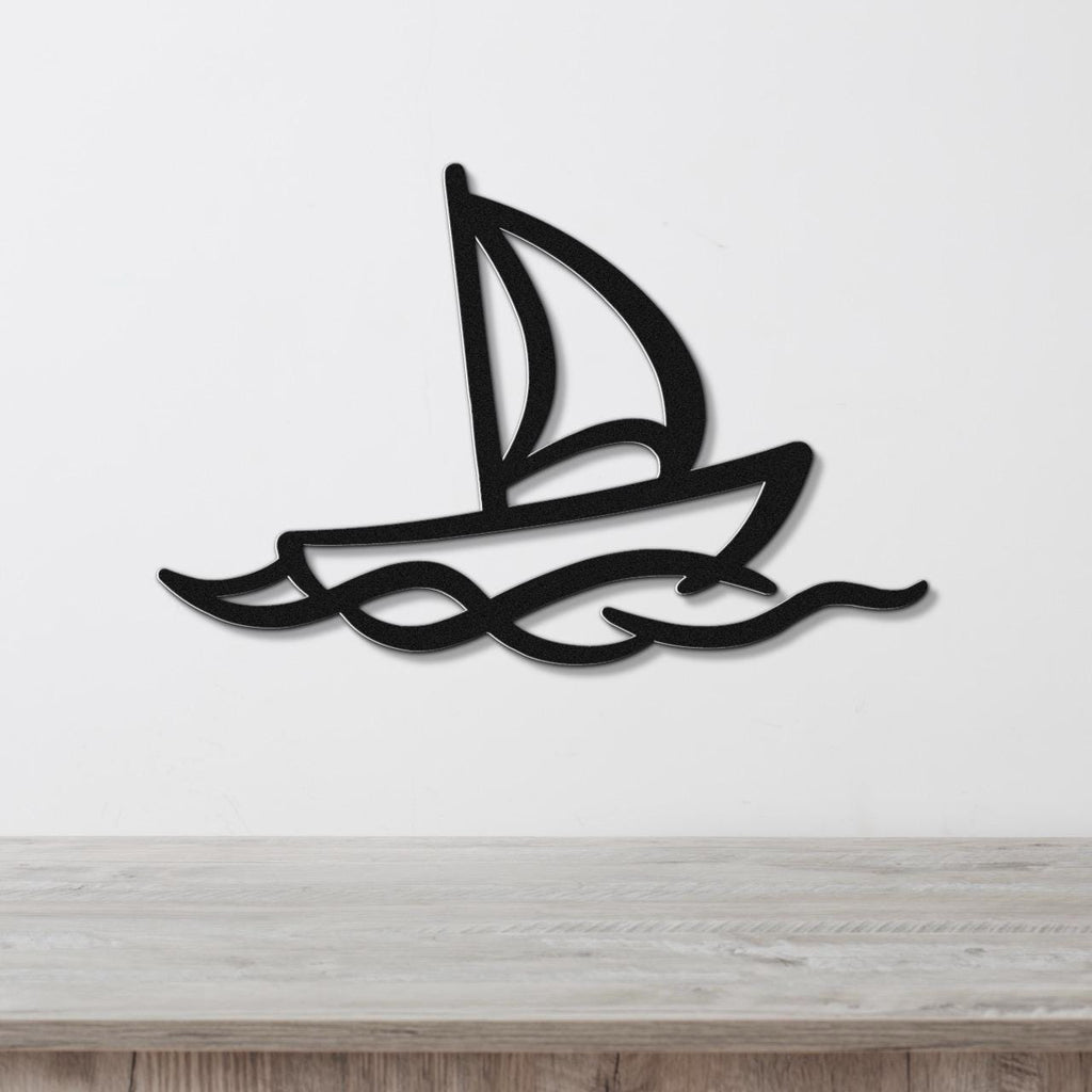 Black metal sailboat wall art with wave cutouts, mounted on a white wall above a wooden surface.