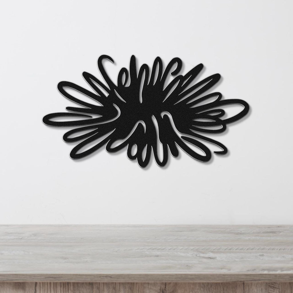 Black metal sea urchin wall art with spiky, radiating cutouts, mounted on a white wall above a light wood surface.