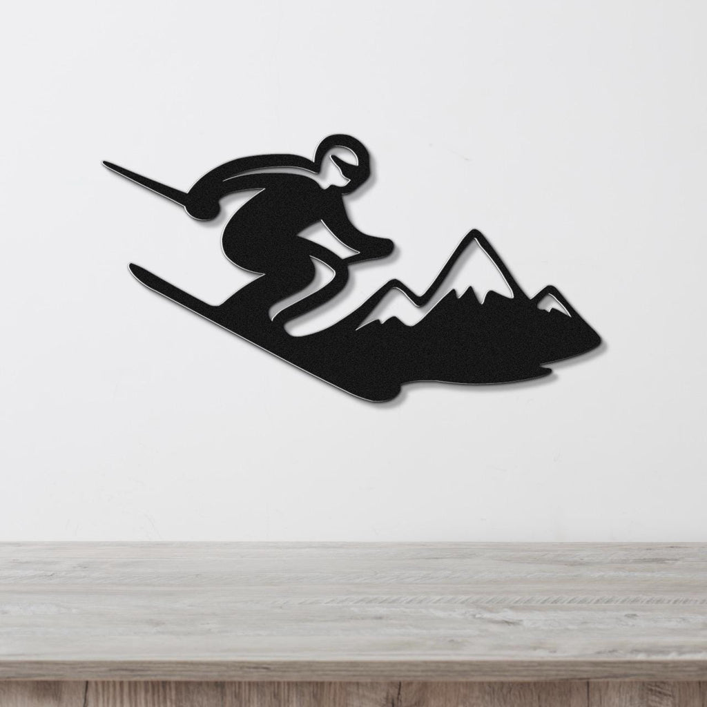 Black metal wall art silhouette of a skier in motion above a mountain range, mounted on a white wall above a wooden counter.