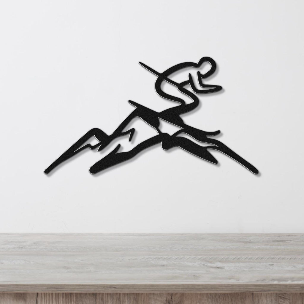Black metal wall art featuring a skier silhouette in motion above mountain peaks, mounted on a white wall above a wooden surface.