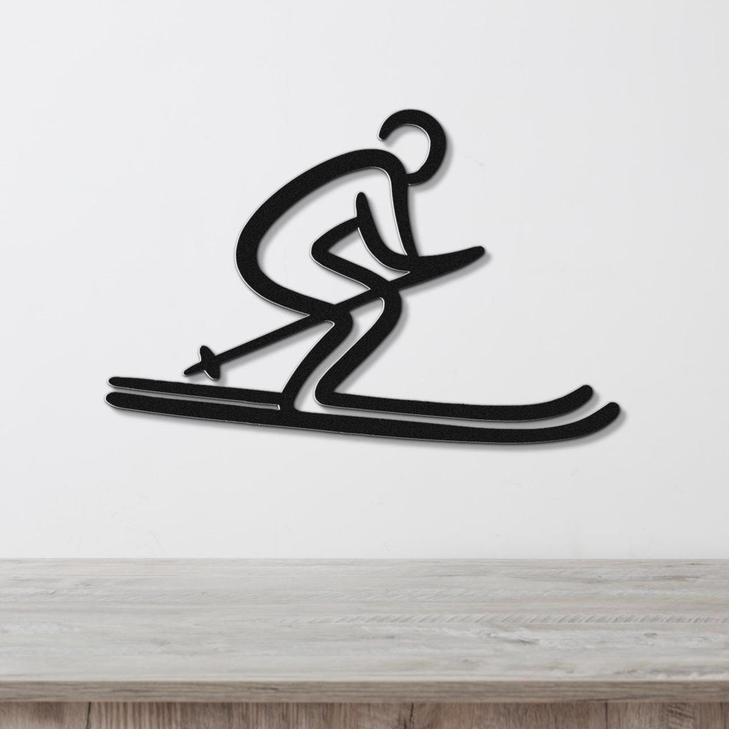 Black metal wall art of a dynamic skier silhouette with cutout details, mounted on a white wall above a light wood surface.