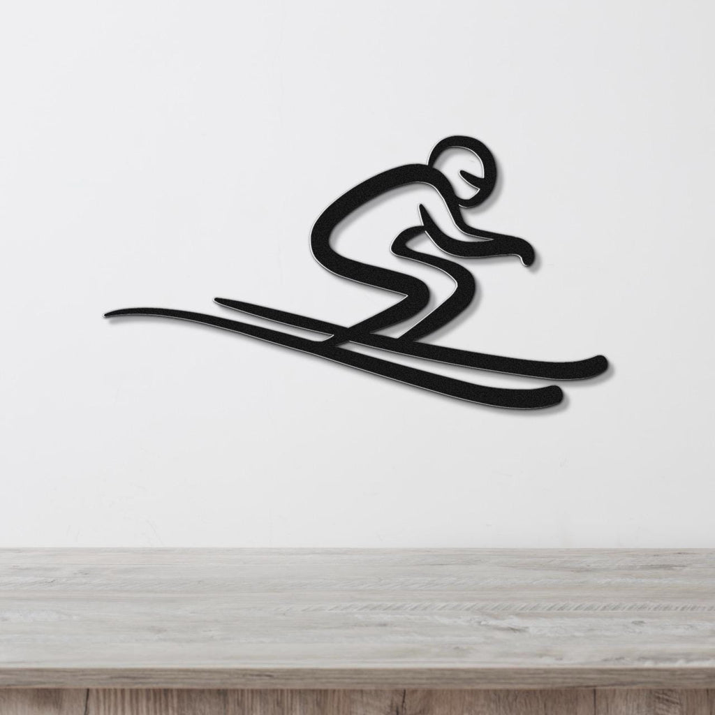 Black metal wall art featuring a minimalist skier silhouette in a crouched pose with long skis, mounted on a white wall above a wooden surface.