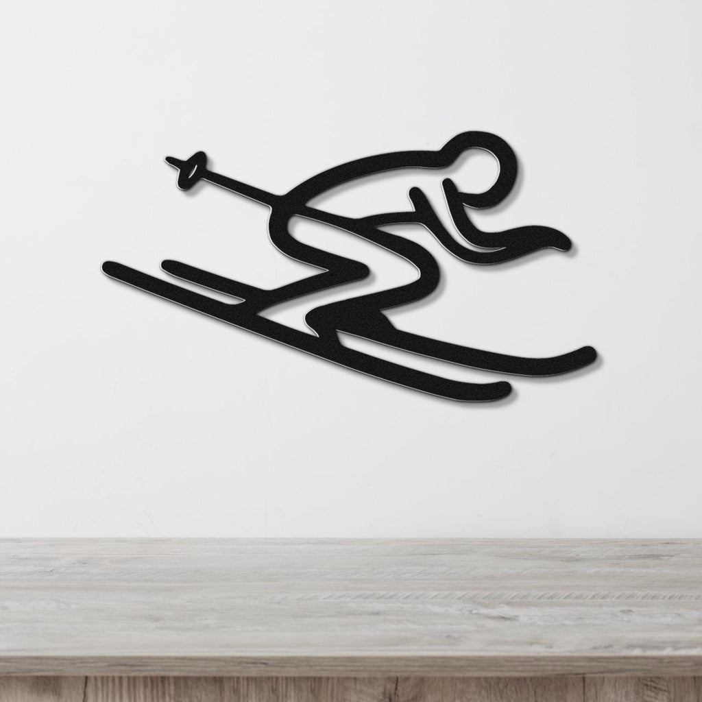 Black metal wall art in a minimalist skiing silhouette design with motion lines, mounted on a white wall above a light wood counter.