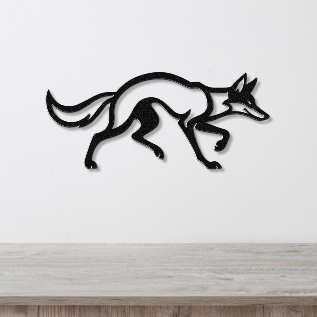 Black metal coyote wall art with a sleek silhouette and motion-line cutouts, mounted on a white wall above a light wood counter.