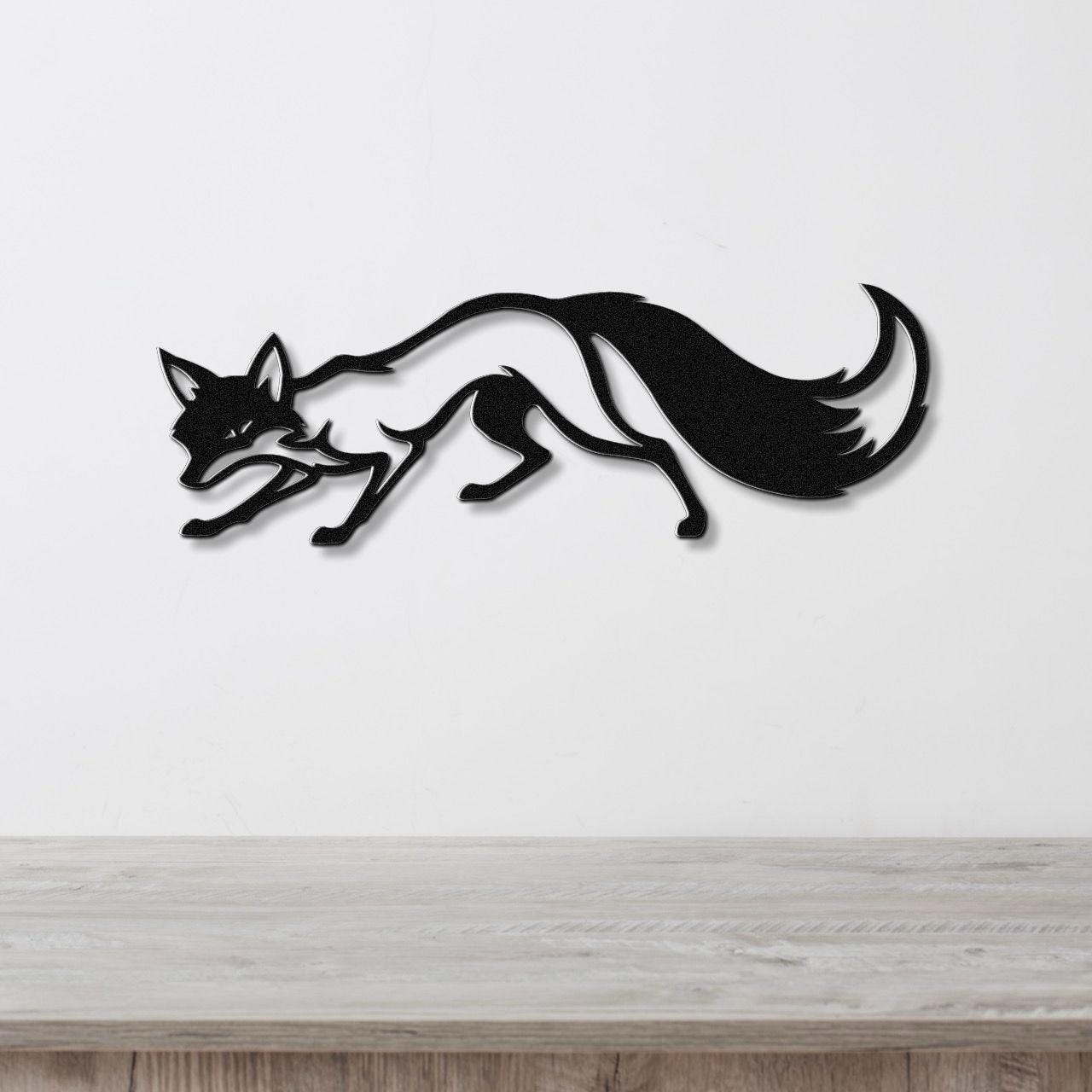 Black metal fox wall art in a leaping silhouette, mounted on a white wall above a light wood surface.