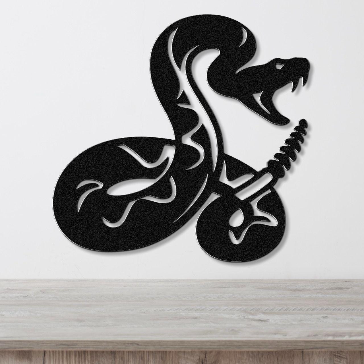 Black metal wall art featuring a coiled snake silhouette with internal cutout details, mounted on a white wall above a light wood surface.