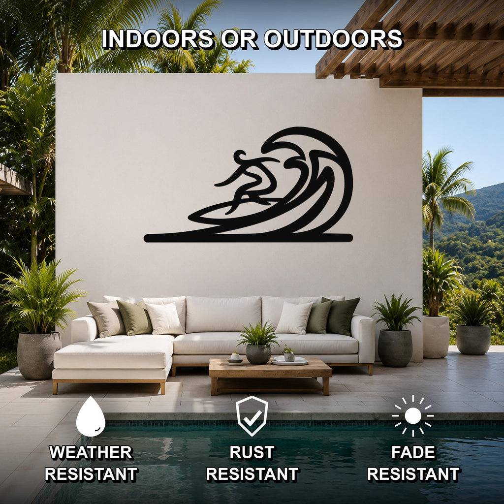 Black metal wall art featuring a surfer silhouette riding a flowing wave, mounted on a white outdoor wall above a sofa in a patio living area.