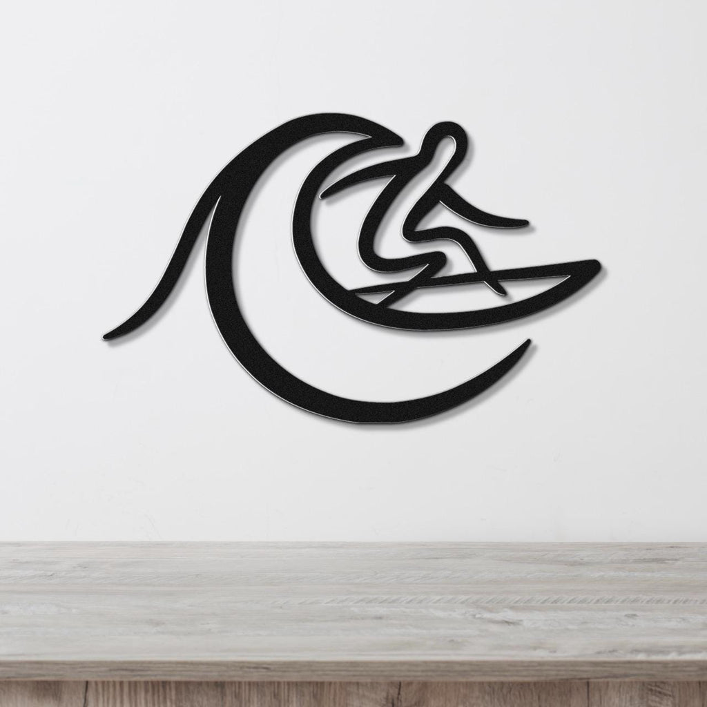 Black metal wall art featuring a surfer silhouette riding a wave, mounted on a white wall above a light wood surface.
