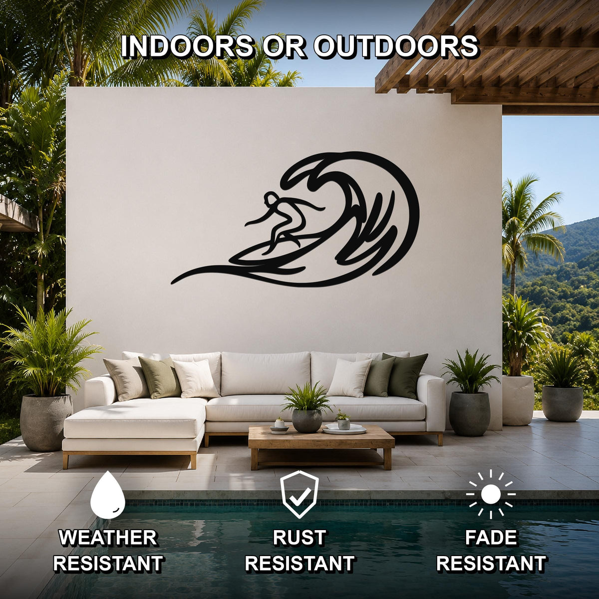 Black metal surfer wall art with wave cutout, mounted on a white outdoor wall above a sofa in a patio living area.