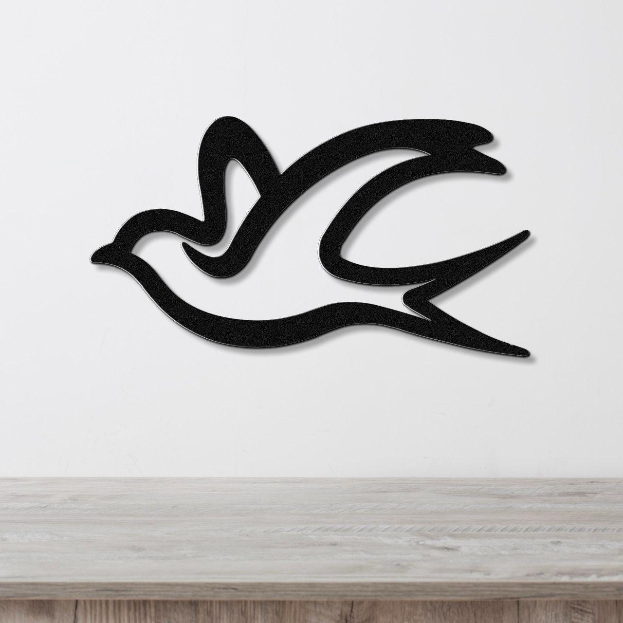 Black metal swallow bird wall art with flowing silhouette cutouts, mounted on a white wall above a light wood countertop.